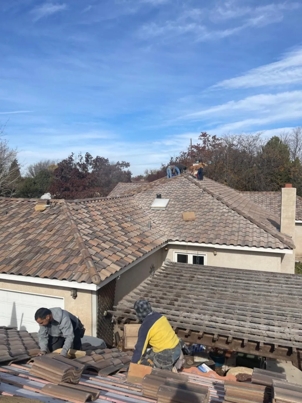 Crew installing tile roofing on a stucco home